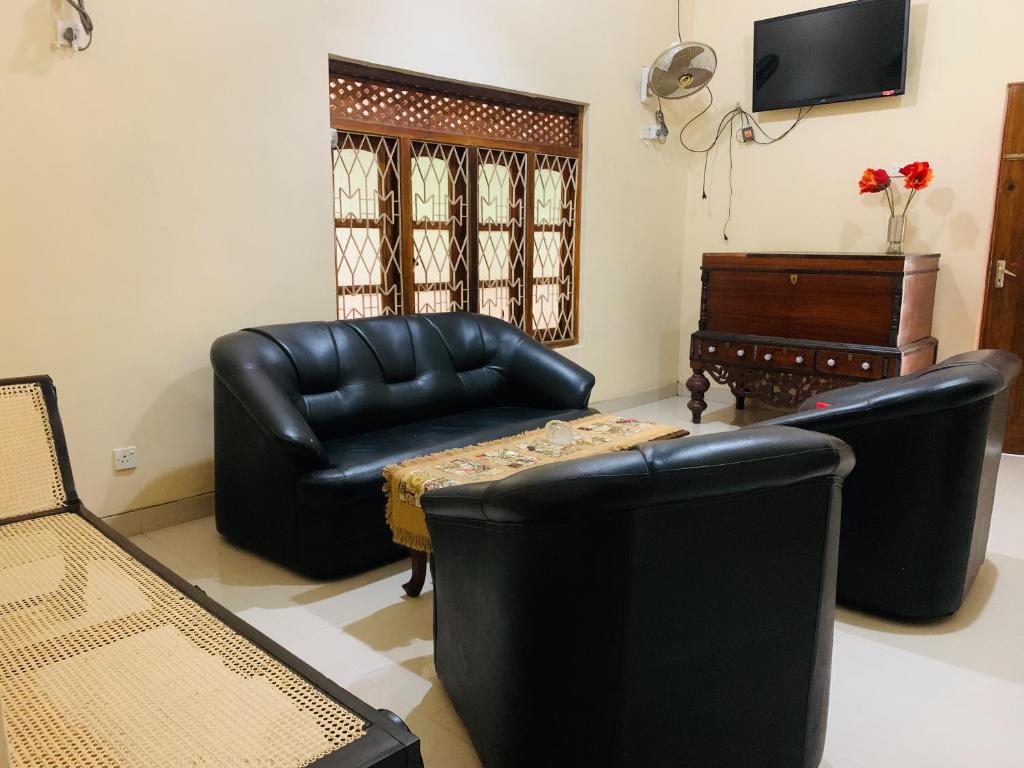 a living room with black leather furniture and a tv at Four Seasons Villa in Anuradhapura