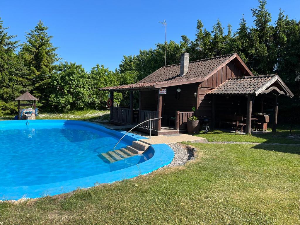 a large swimming pool in front of a cabin at Agroturystyka w Łęgowie, Domki na Mazurach in Olecko