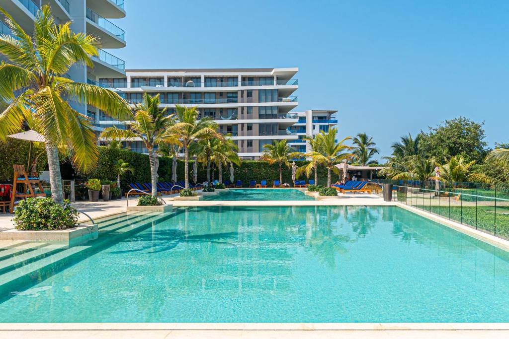 une grande piscine bordée de palmiers et un bâtiment dans l'établissement Loft de Lujo Cartagena - Salida Directa Al Mar - Piscinas - Jacuzzi en Morros, à Carthagène des Indes