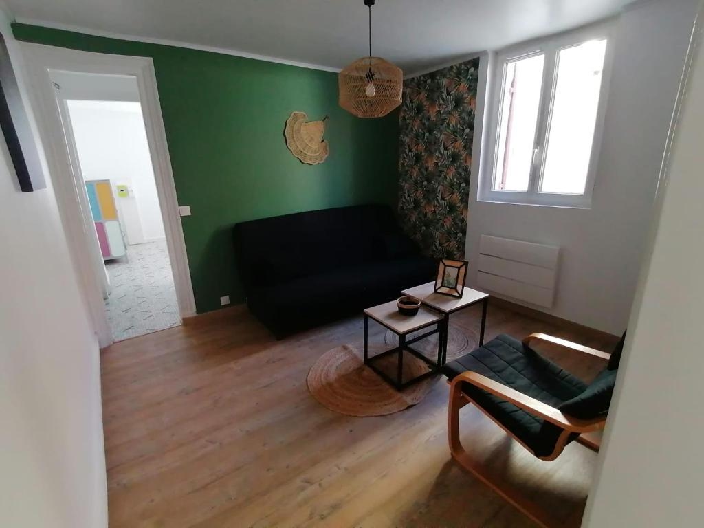 a living room with a black couch and a table at Logement Soulac-sur-mer 4 personnes in Soulac-sur-Mer