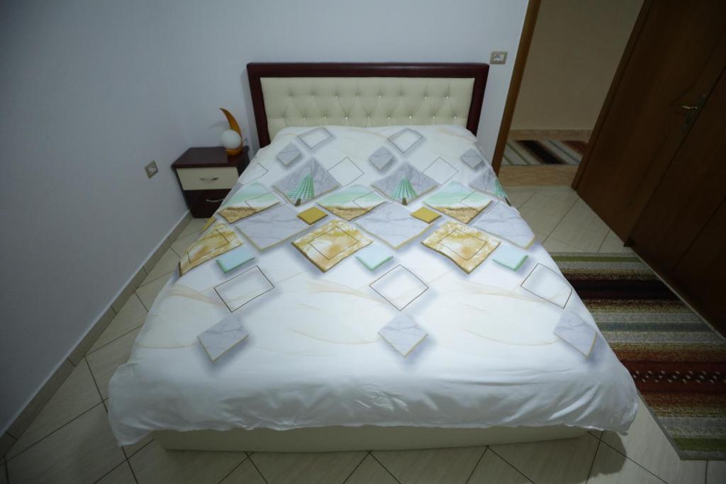 Una cama blanca con plazas en una habitación en Vila Antigonea en Gjirokastër
