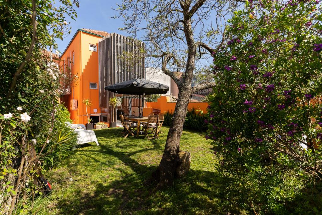 un patio con una mesa y una sombrilla en el césped en Peach Hostel & Suites, en Oporto