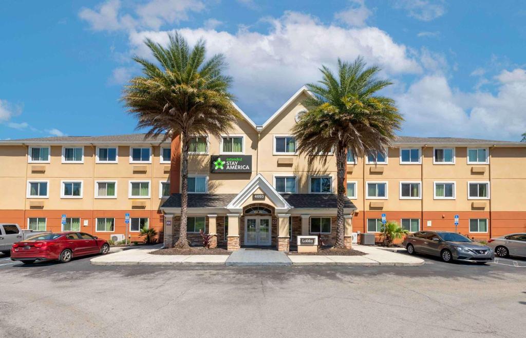 a hotel with two palm trees in front of it at Extended Stay America Select Suites - Jacksonville Salisbury Rd Southpoint in Jacksonville