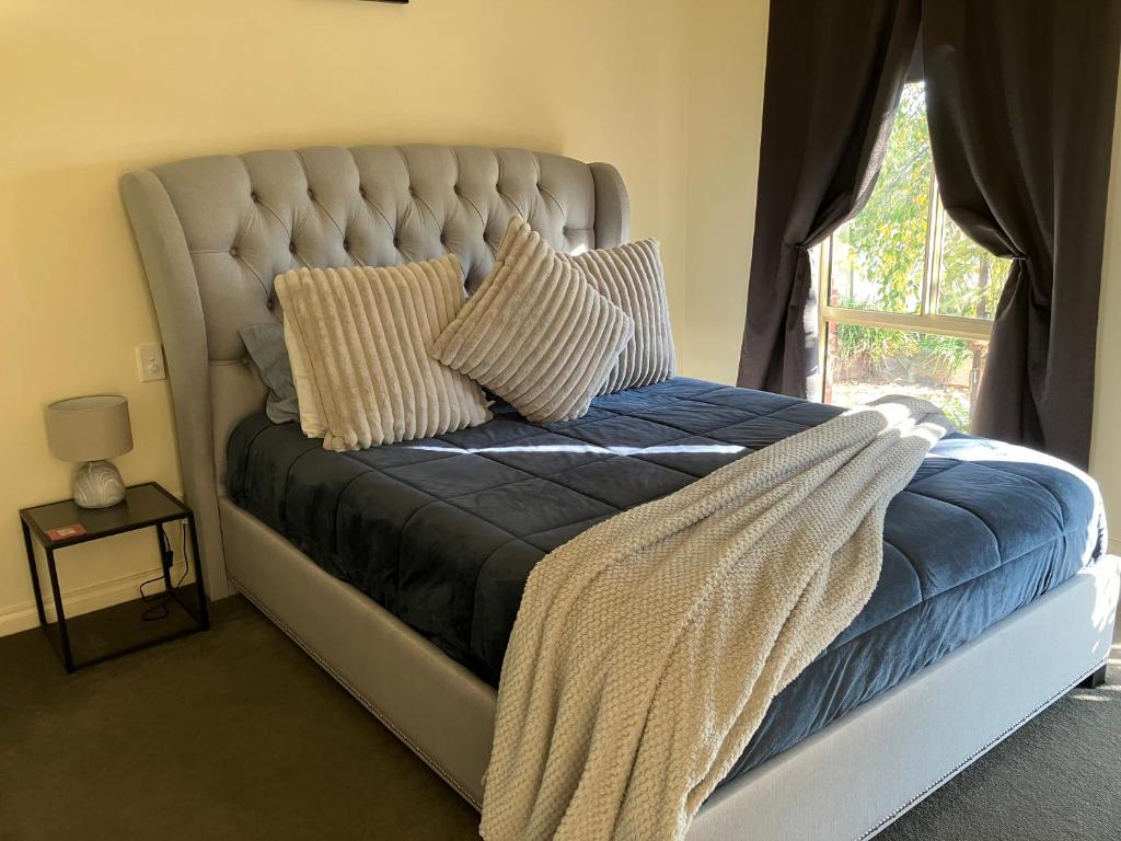 a bed with a blue blanket and a window at James Court Suite in Rutherglen