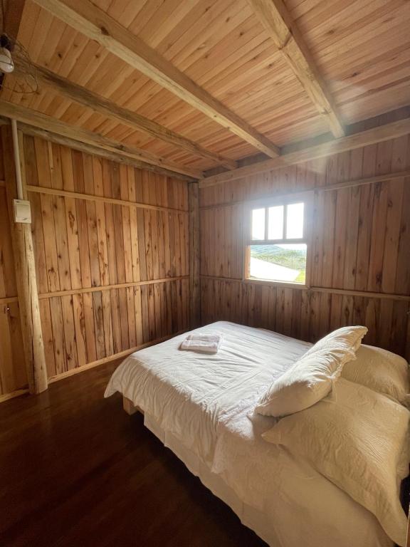 ein Schlafzimmer mit einem Bett in einem Holzzimmer in der Unterkunft Casa de Campo Gralha Azul in Bom Jardim da Serra