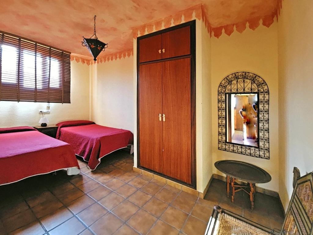 1 dormitorio con 2 camas, mesa y espejo en Casas Rurales Los Molinos en Sanlúcar de Guadiana