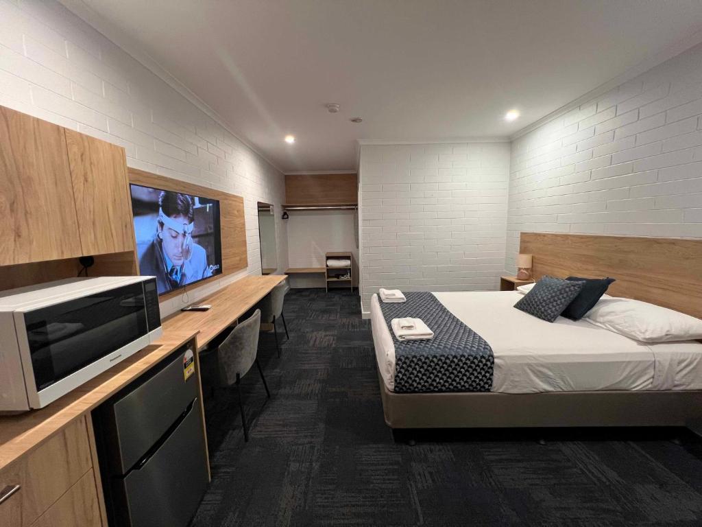 ein Schlafzimmer mit einem Bett und einem TV in einem Zimmer in der Unterkunft Katherine Motel in Katherine