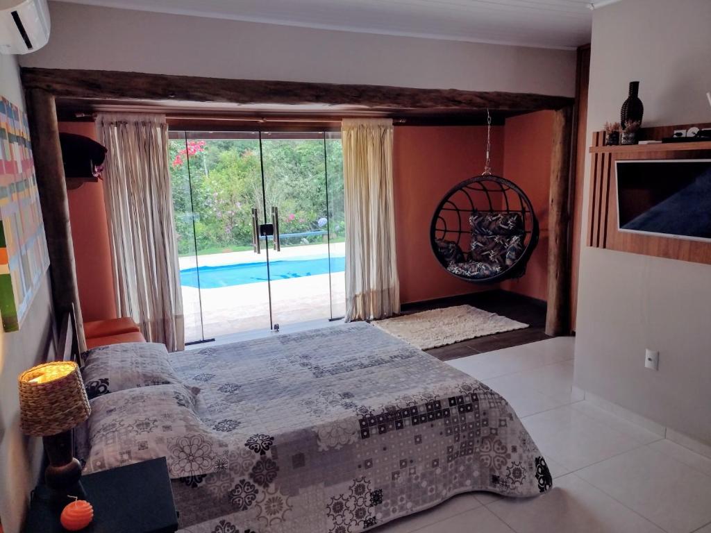 een slaapkamer met een bed en uitzicht op een zwembad bij Sítio Cachoeirinha in Marechal Floriano