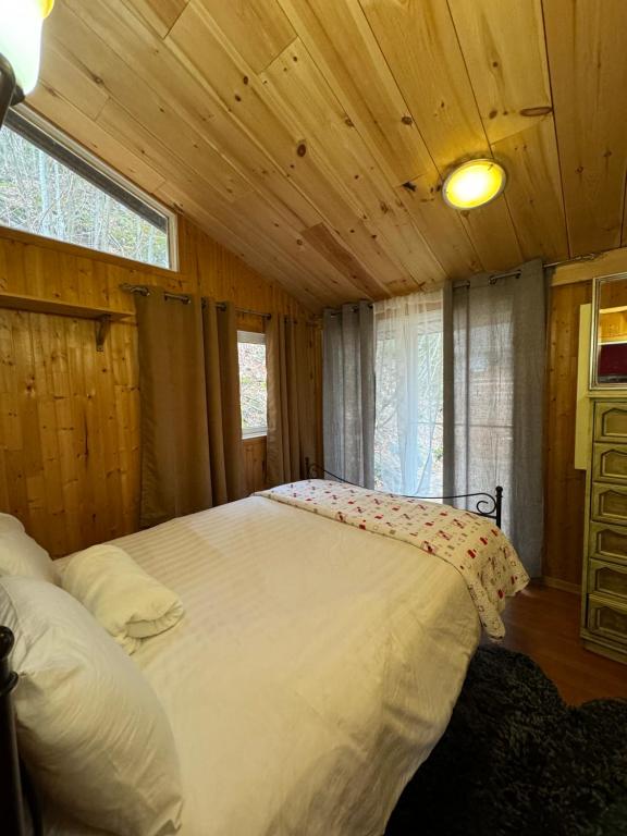 ein Schlafzimmer mit einem großen weißen Bett in einer Hütte in der Unterkunft Chalet Alpin Suisse Au Bord Du Lac in Morin Heights