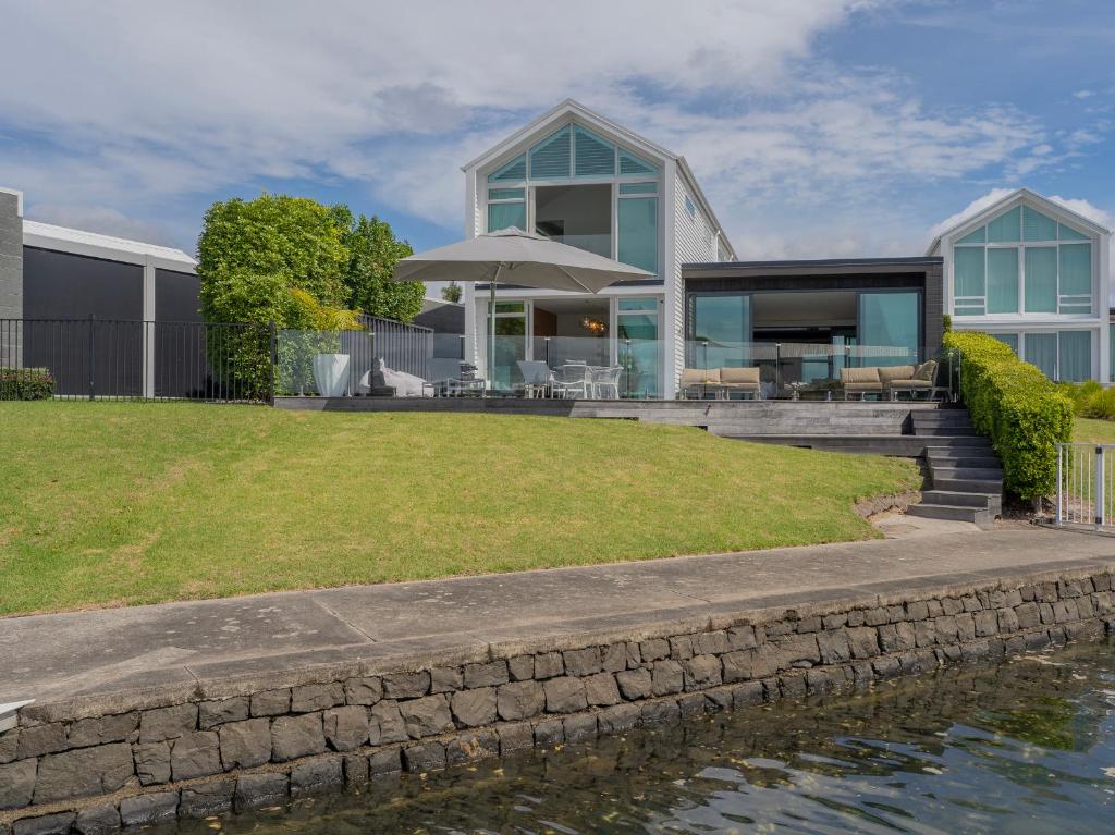 a house on the water with a stone wall at Villa Viti - Pauanui Holiday Home in Pauanui