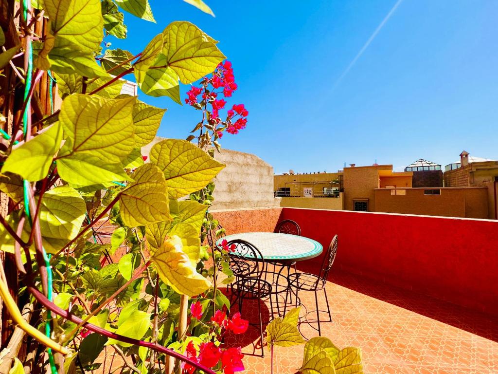 einen Tisch und Stühle auf einem Balkon mit Blumen in der Unterkunft Sabor Family Aparts JAWHARAT AL ATLAS in Marrakesch