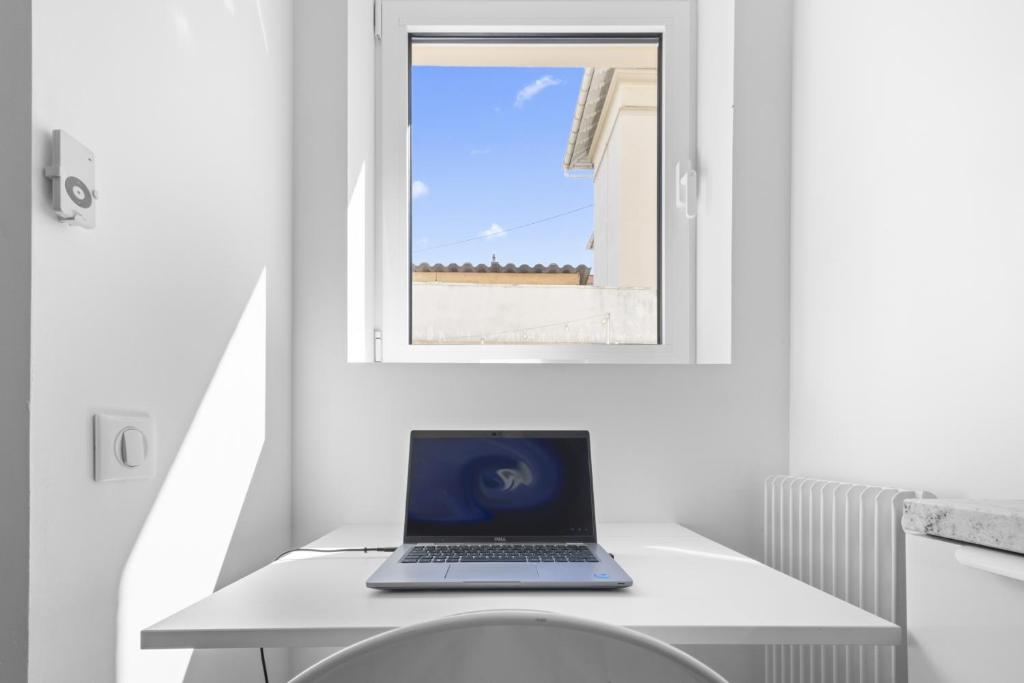 a laptop sitting on a white desk in a room at Cannes NG - Appartement à 10 mn du Palais des Festivals in Cannes