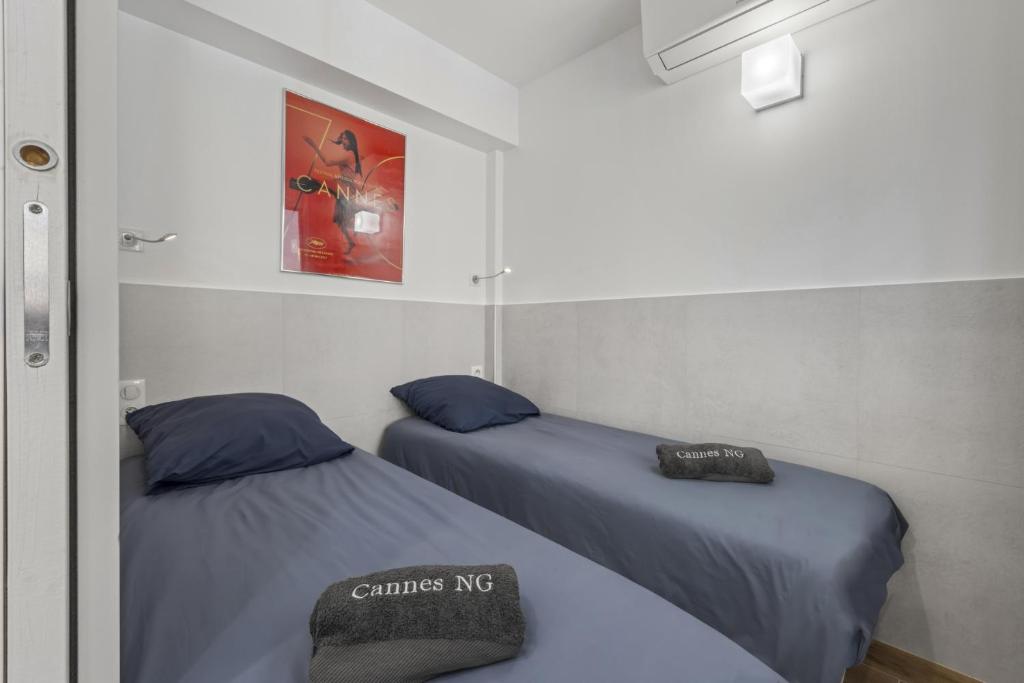 two beds in a room with a picture on the wall at Cannes NG - Appartement à 10 mn du Palais des Festivals in Cannes