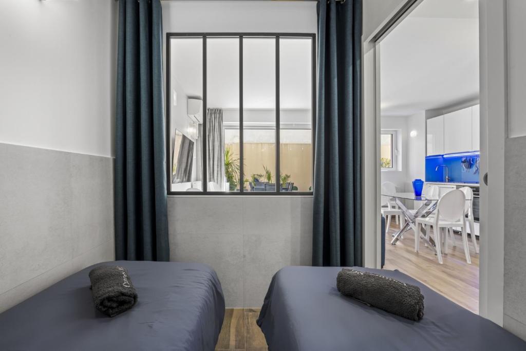 two beds in a room with a window and a dining room at Cannes NG - Appartement à 10 mn du Palais des Festivals in Cannes