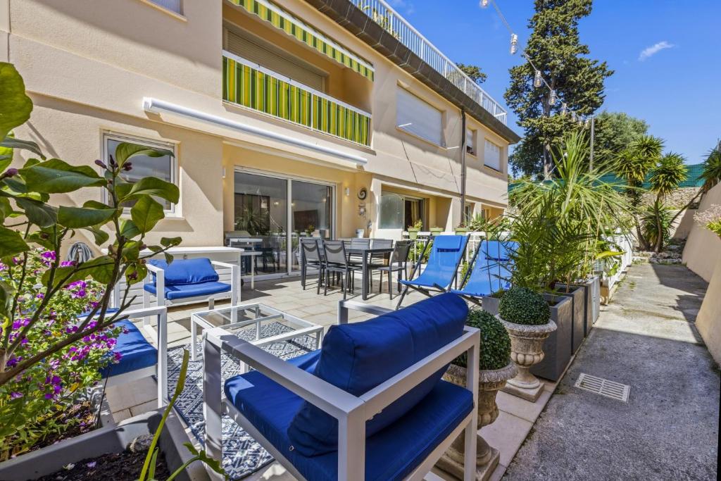 a patio with blue chairs and tables and plants at Cannes NG - Appartement à 10 mn du Palais des Festivals in Cannes