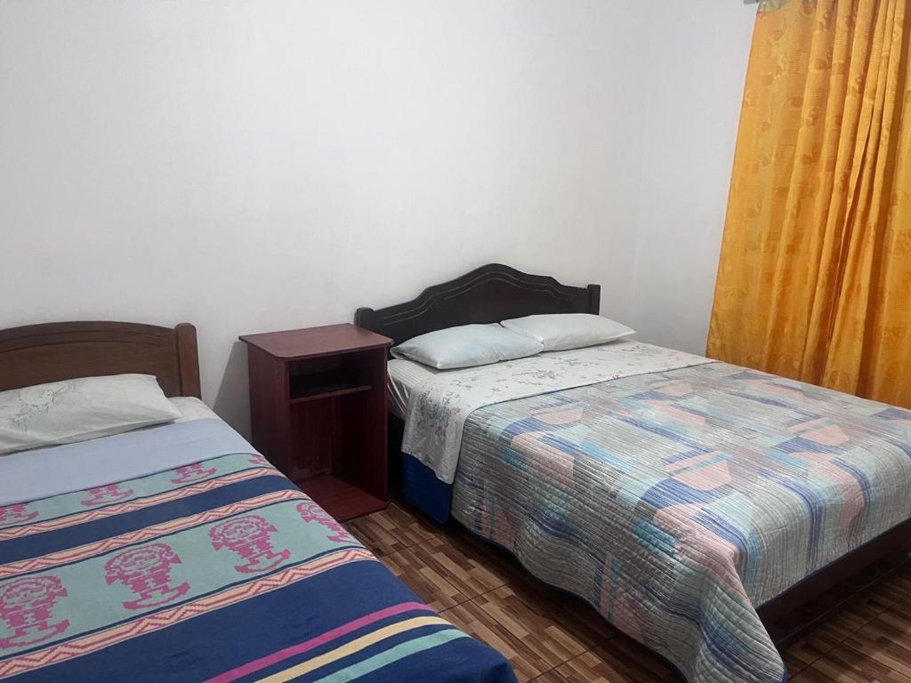 a bedroom with two beds and a night stand with a bedskirts at Las tres cruces in Arica