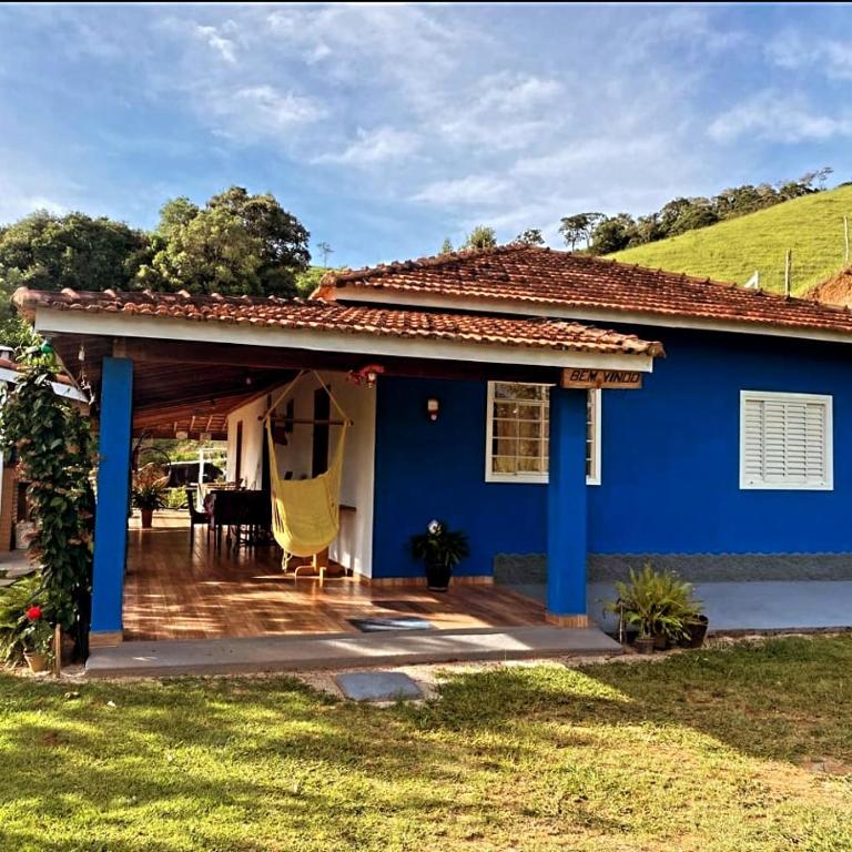 a blue house with a porch with a deck at Estalagem Sitio Colibri in Cunha