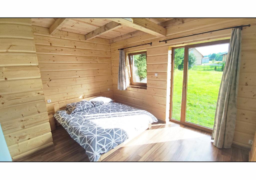 Łóżko w drewnianym pokoju z oknem w obiekcie Chata Wilka - całoroczny dom z bali na wyłączność z 3 sypialniami w mieście Brzegi Dolne