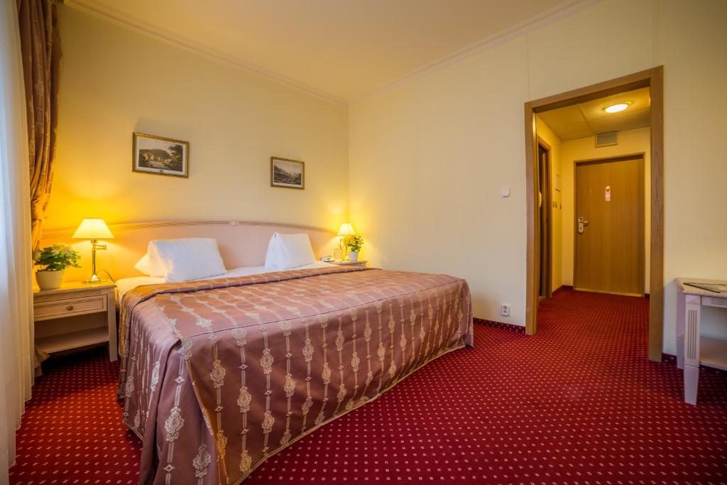 a hotel room with a large bed and a red carpet at Interhotel Central in Karlovy Vary