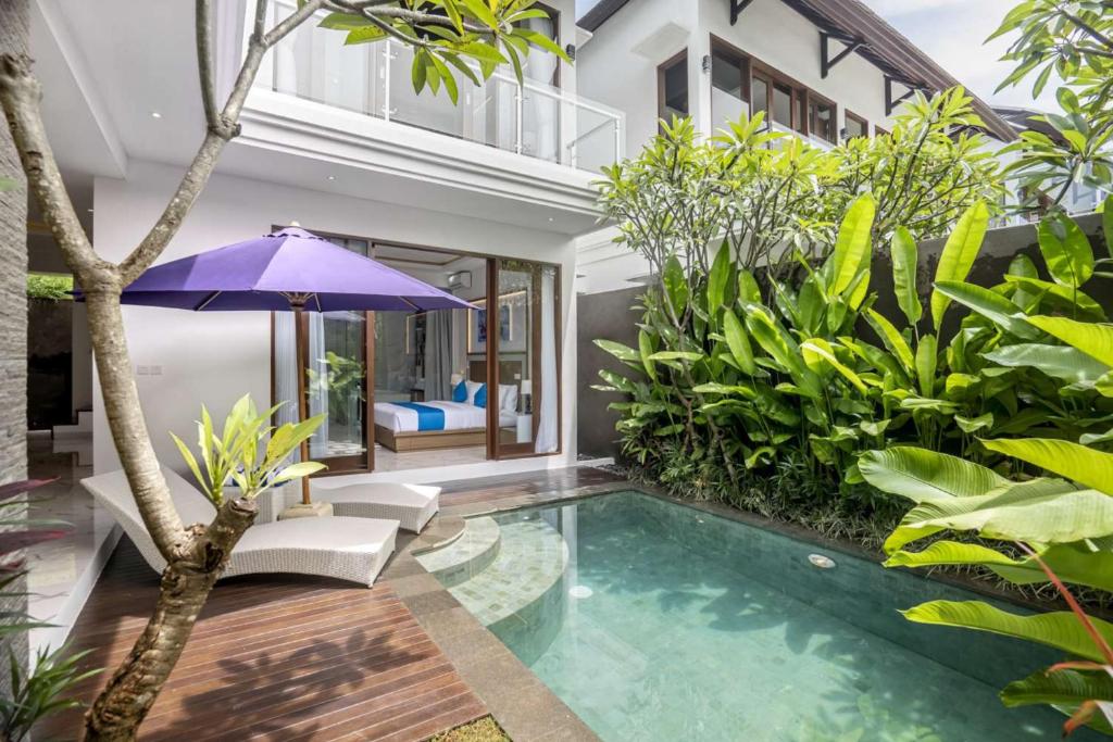 a house with a swimming pool with a purple umbrella at Villa Sun Lila by JB Villas in Seminyak
