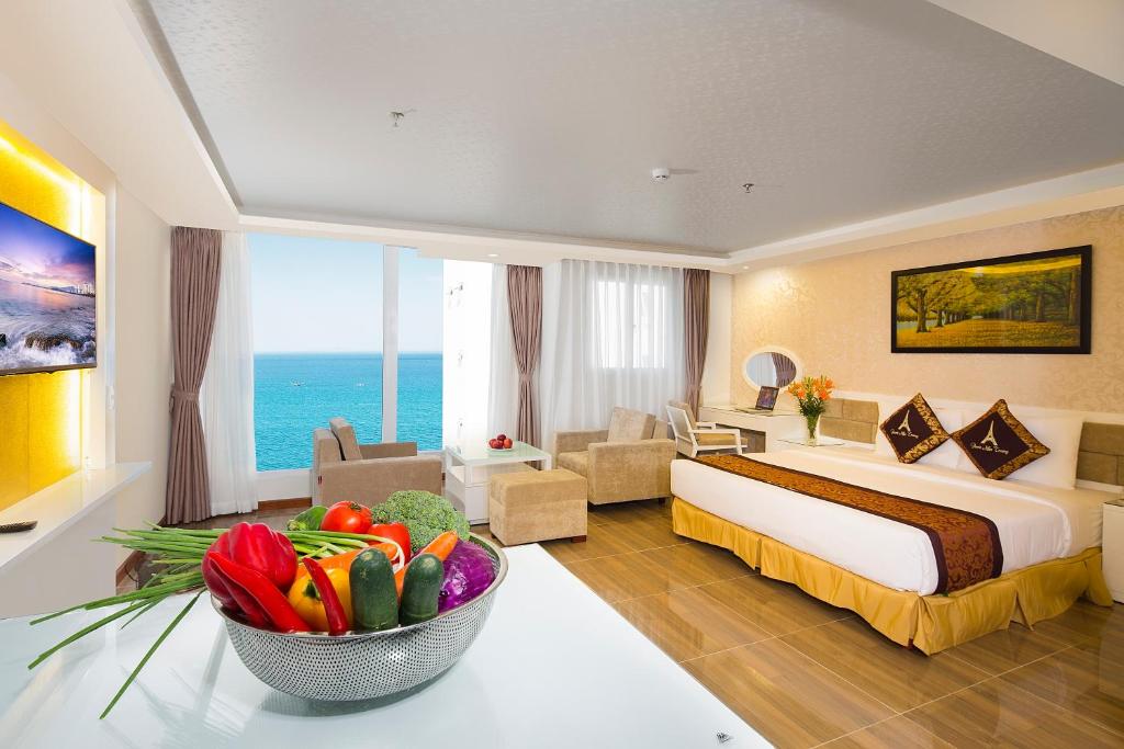 une chambre d'hôtel avec un lit et un bol de fleurs dans l'établissement Paris Nha Trang Hotel, à Nha Trang