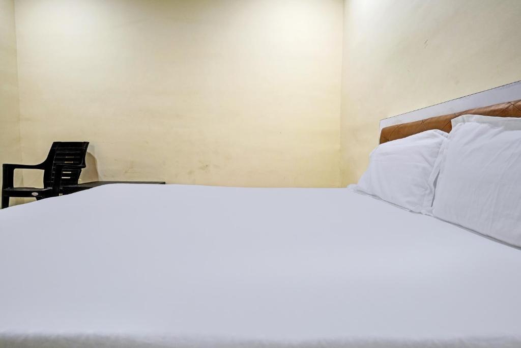 Una cama con almohadas blancas y una silla en una habitación en OYO Sai Villa Lodging & Bording, en Bombay