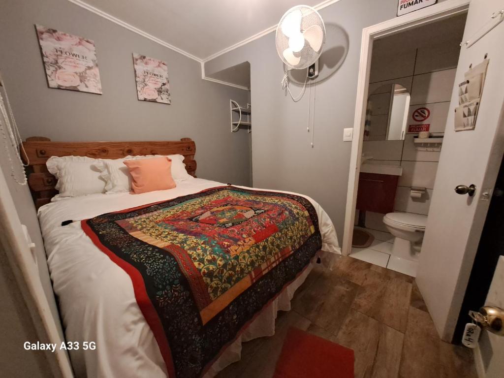 a bedroom with a bed and a bathroom with a toilet at HOSTAL EL AROMO.. in Chillán