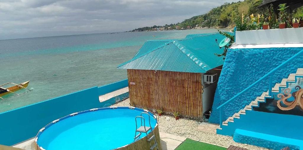 a blue building with a swimming pool next to the ocean at MLK Bamboo Beachhouse in Alegria