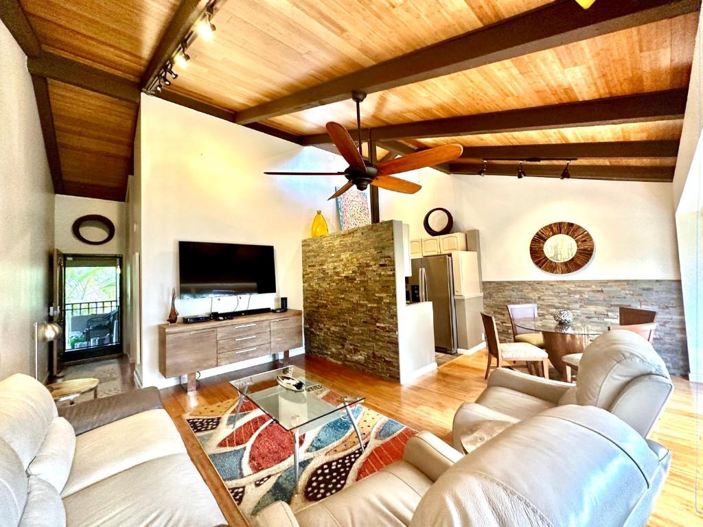 a living room with white furniture and a ceiling fan at Modern Kahana getaway in Kahana
