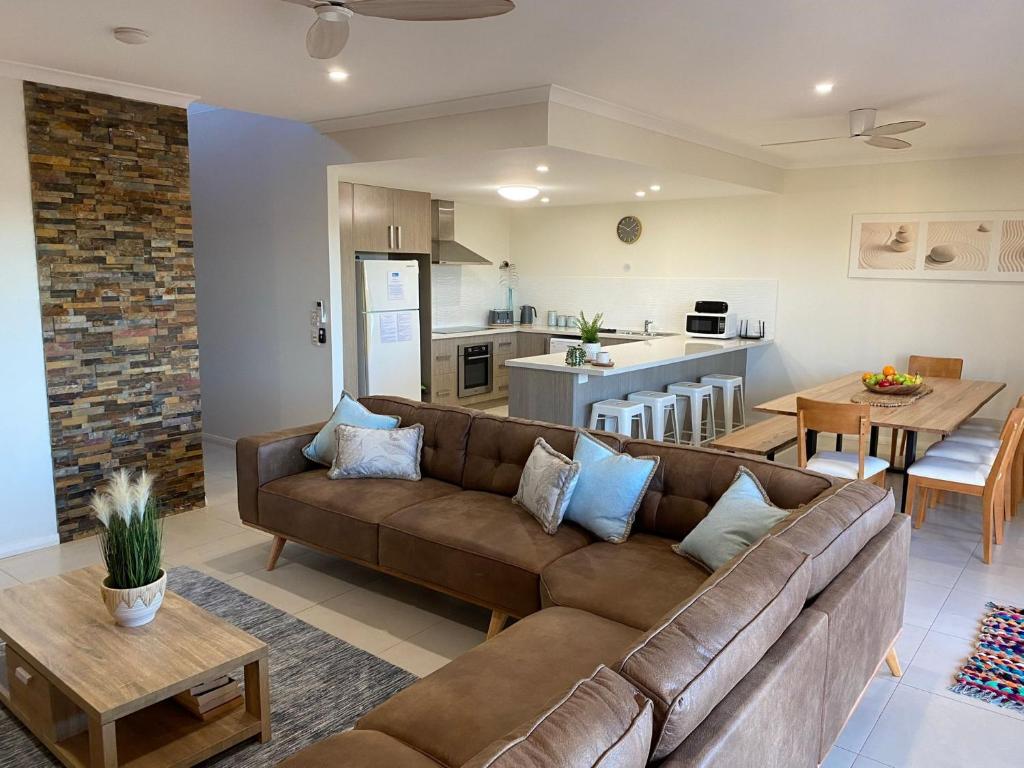 sala de estar con sofá marrón y cocina en 35 Bluefin Cove, en Exmouth