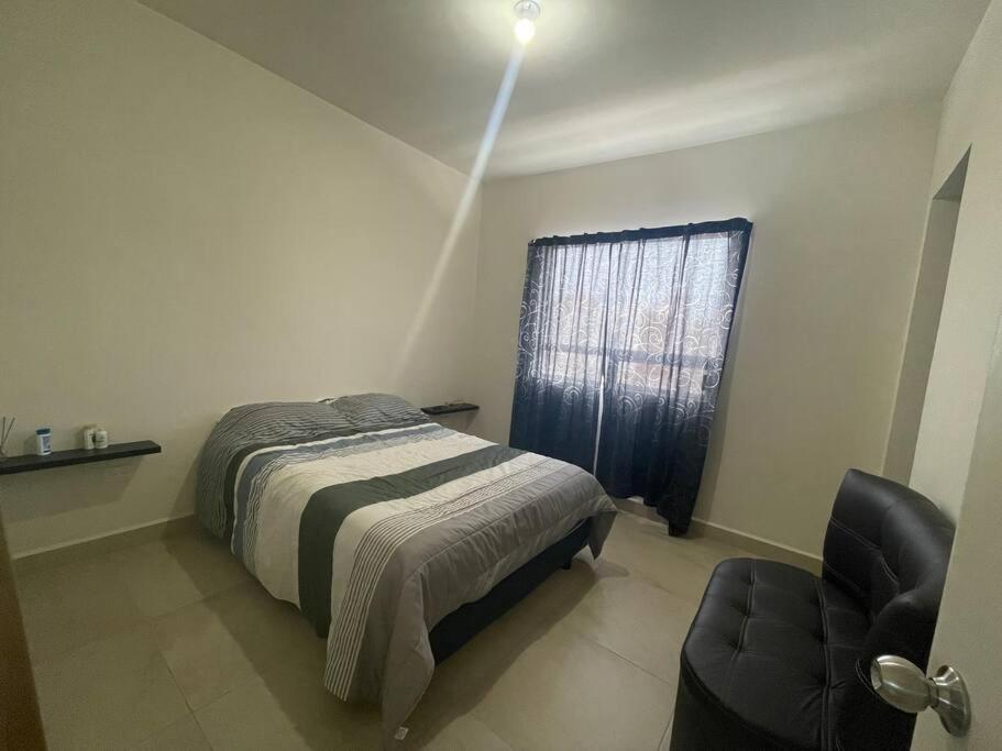 a bedroom with a bed and a chair and a window at Casa santeli miramar in Ciudad Madero