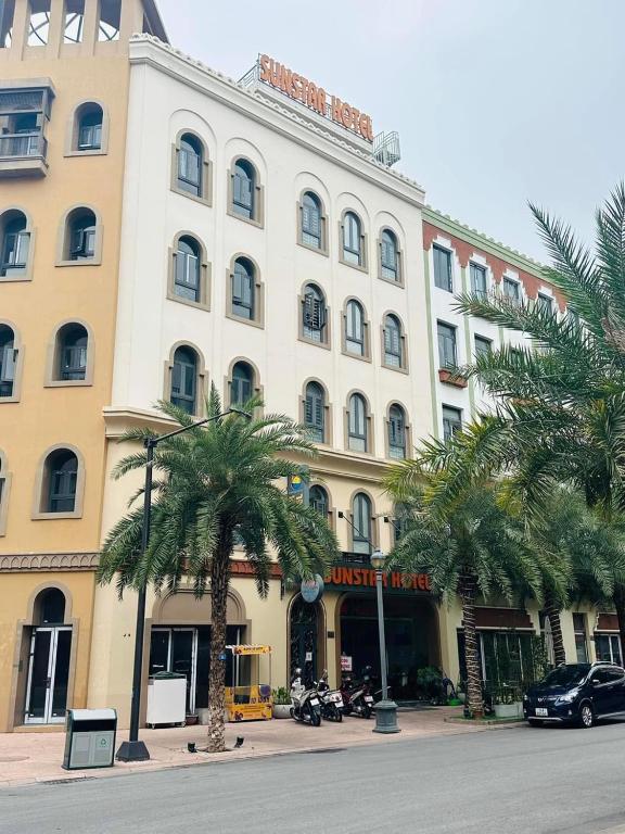 un gran edificio blanco con palmeras delante en Sunstar Hotel, en Ha Long