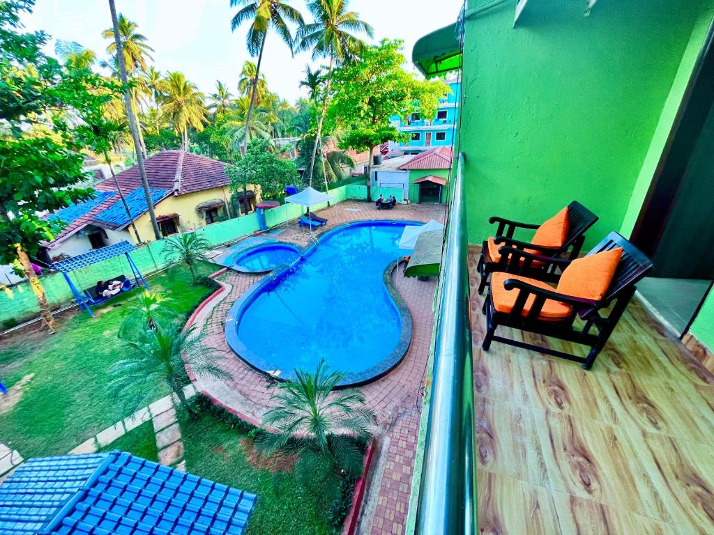 a balcony with a swimming pool and two chairs at Hotel The Golden Shivam Resort - Big Swimming Pool Resort In Goa in Goa
