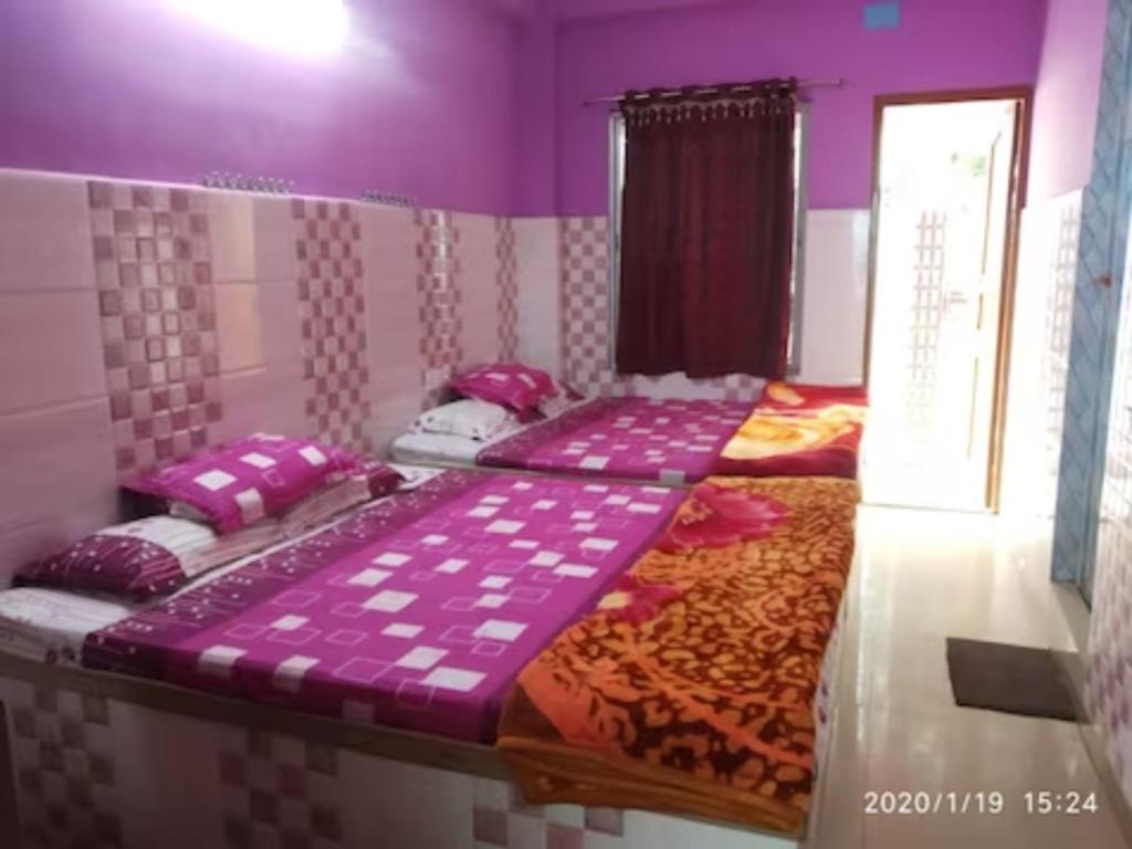 2 Betten in einem Zimmer mit lila Wänden in der Unterkunft Hotel Milan Guest House Digha - Couple Friendly in Digha