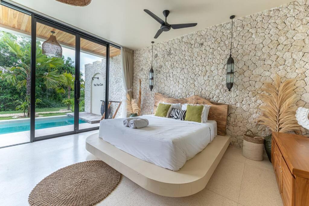 a bedroom with a large bed and a wall of windows at Stylish Tropical Villa in Uluwatu in Uluwatu
