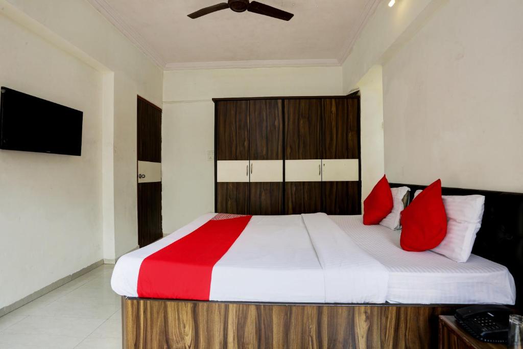 a bedroom with a large bed with red pillows at Hotel Lal Sai Residency in Mumbai