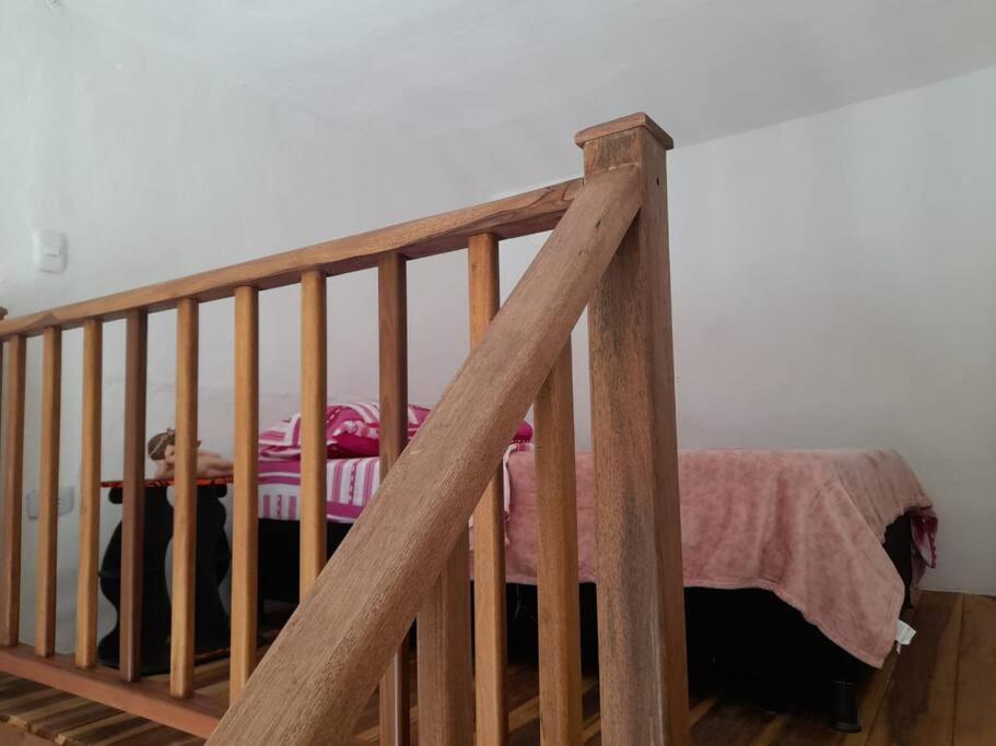 a bedroom with a bed and a wooden stair railing at Apartaestudio cerca a parque Zapatoca in Zapatoca