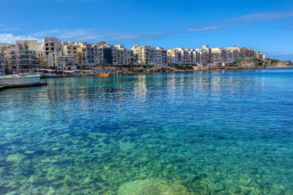 une grande masse d'eau avec des bâtiments en arrière-plan dans l'établissement Green Valley, à Żebbuġ