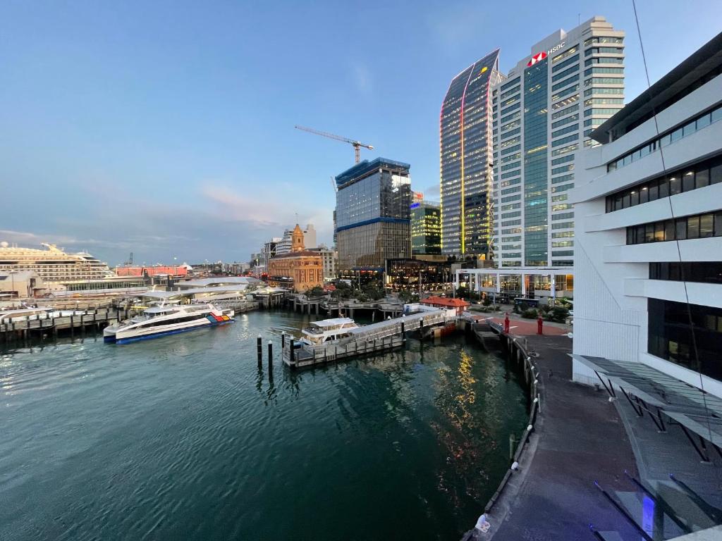 a river with boats in a city with tall buildings at Chic Princes Wharf Studio - City View - Parking in Auckland