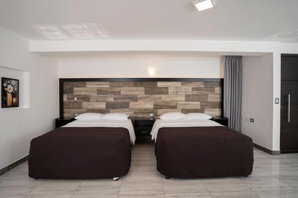 two beds in a room with a brick wall at Hotel Luna de Plata Aeropuerto in Quetzaltenango