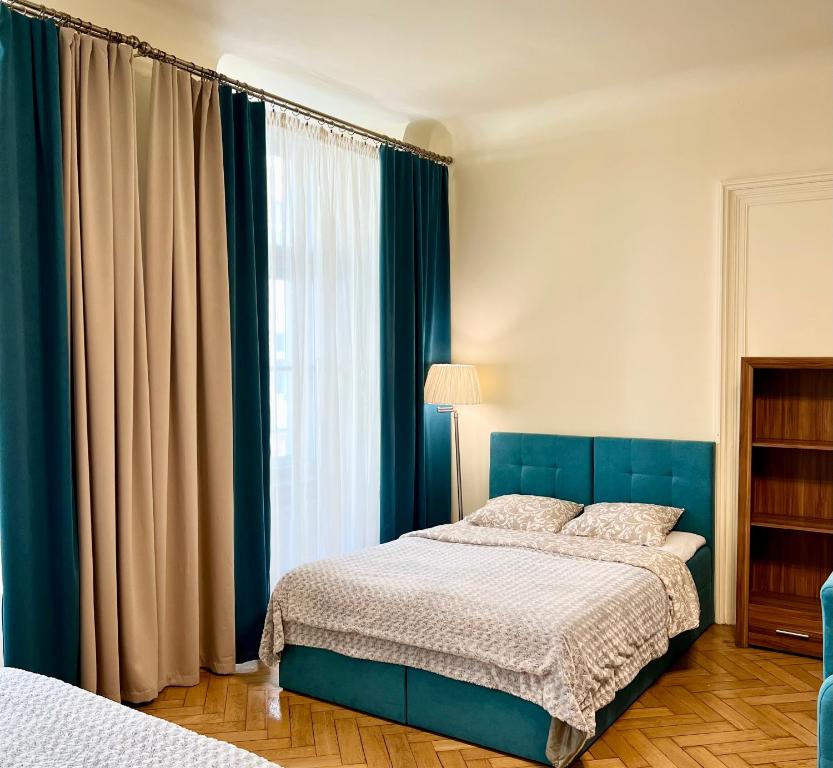 sypialnia z niebieskim łóżkiem i oknem w obiekcie Apartamenty i Studia HERBARIUM w Krakowie