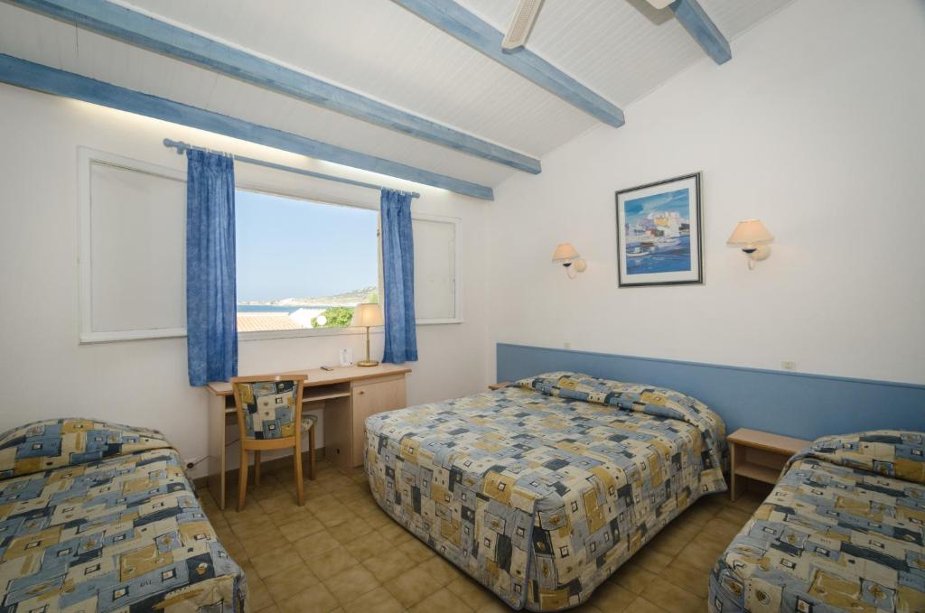 a bedroom with two beds and a desk and a window at Hotel L&#39;ondine in Algajola