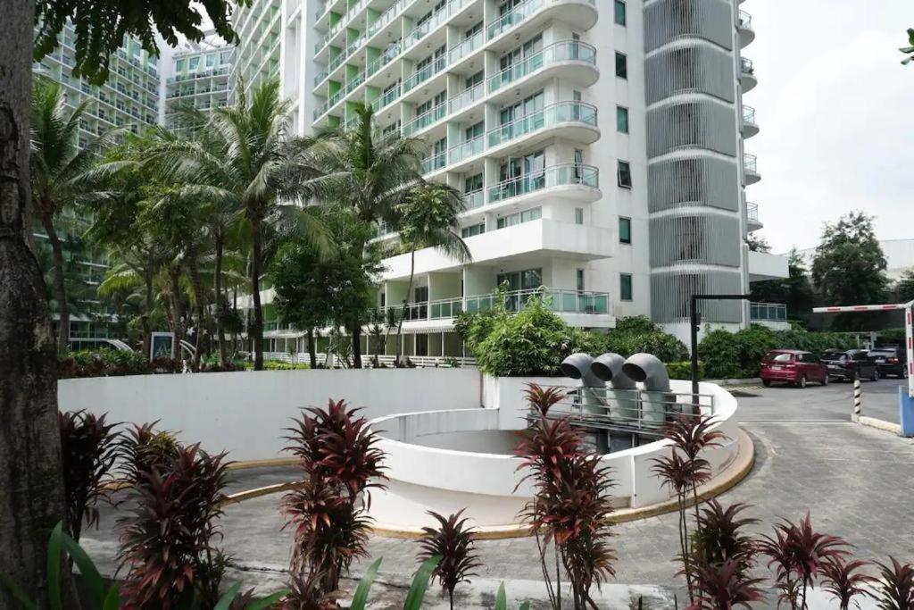 a large white building with palm trees in front of it at Azure Urban Residences Beach and Resort by Vookley in Manila