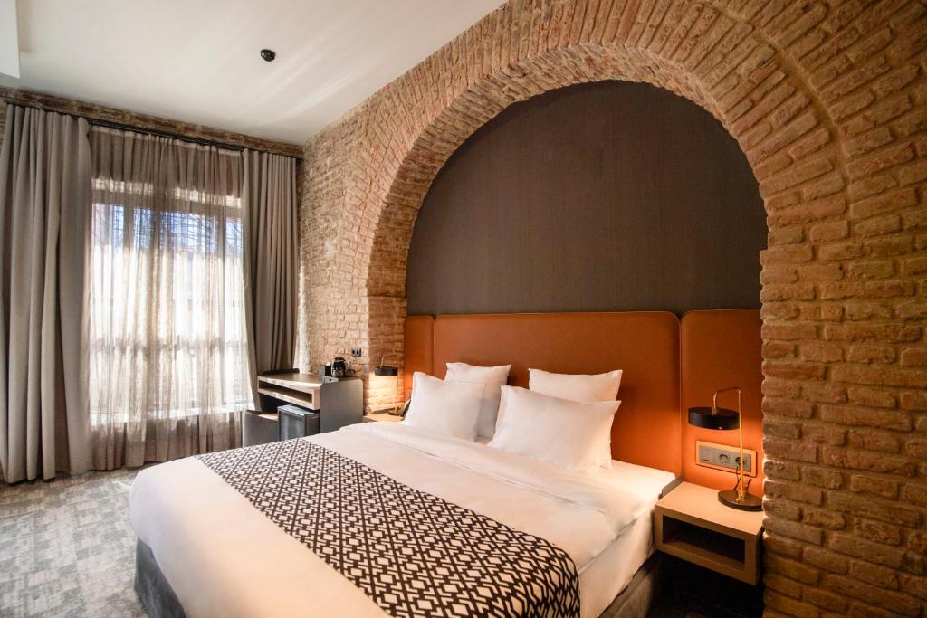 a bedroom with a large bed and a brick wall at Qarvasla Hotel in Tbilisi City