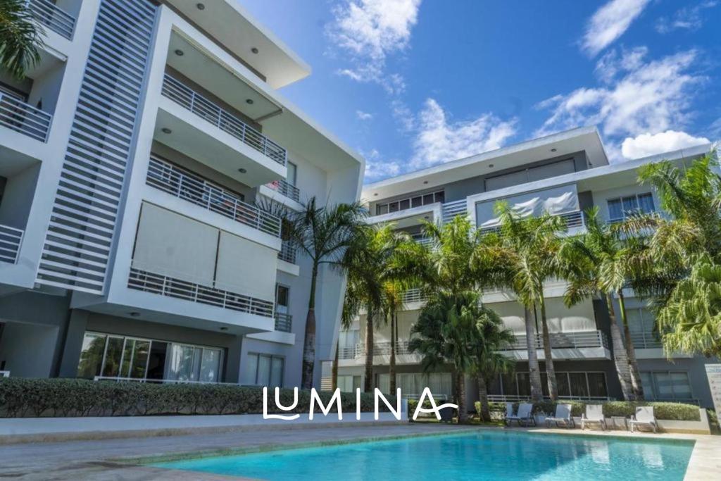 a large building with a swimming pool in front of it at Lumina at Palms Punta Cana Village in Punta Cana
