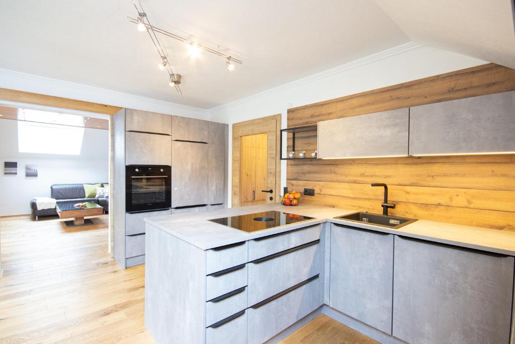 a kitchen with stainless steel cabinets and a living room at Appartement Riedingtal in Zederhaus