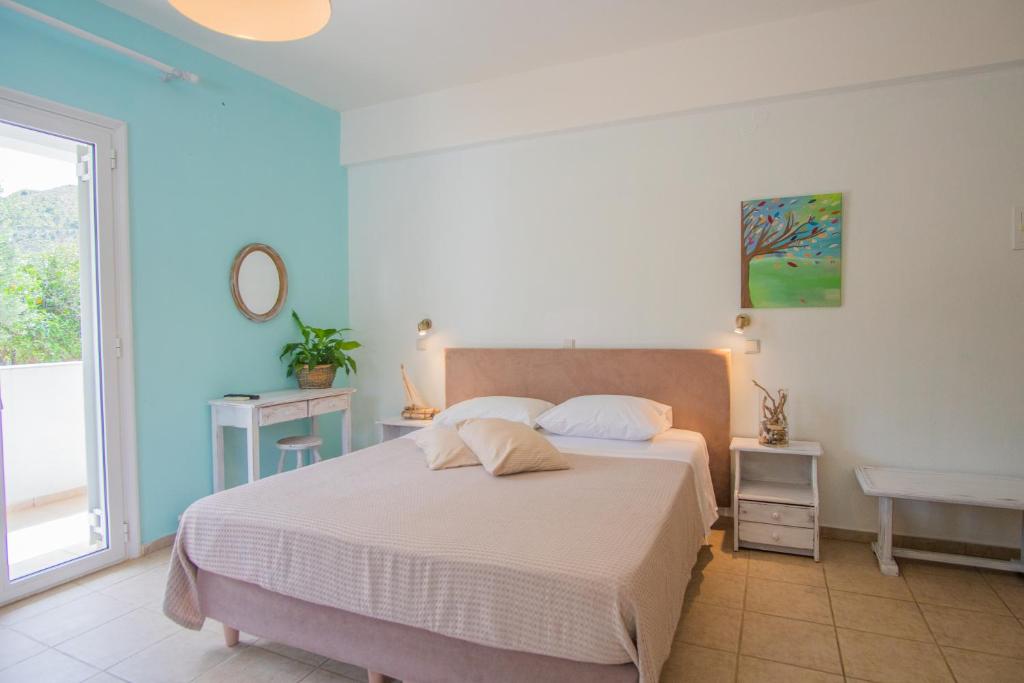 a bedroom with a bed with white sheets and a window at Kassiani Studios in Plakias