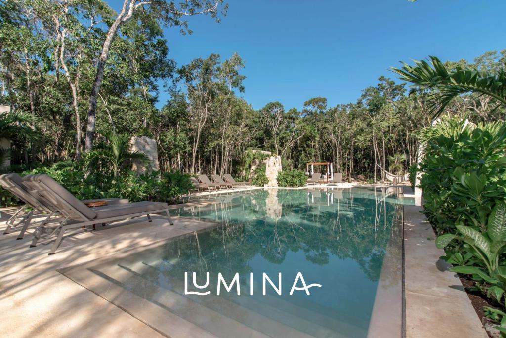 a swimming pool in a villa with trees at Lumina at LOSANTOS Tulum in Tulum