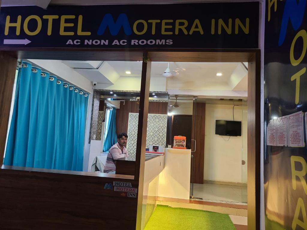 un hombre sentado en un escritorio en una oficina de hotel en Hotel Motera Inn en Ahmedabad