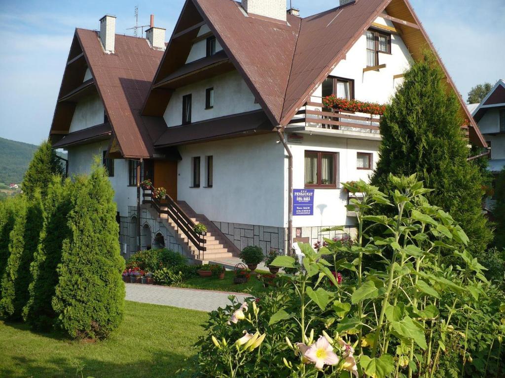 une grande maison blanche avec un toit marron dans l'établissement Willa Anna Maria, à Wysowa-Zdrój